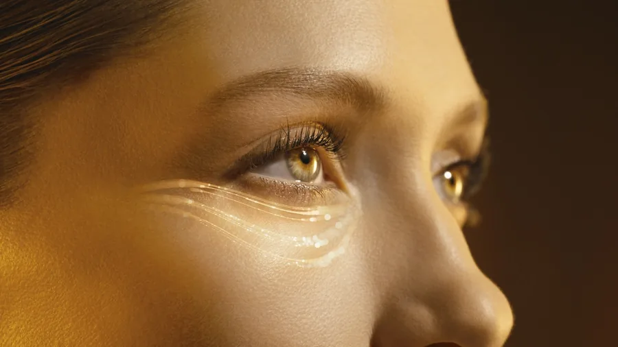 Kampagnenbild von Clarins zu Double Serum Eye: Augenpartie einer Frau mit glänzenden Serumspuren im warmen Licht